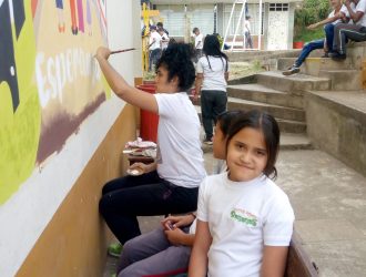 estudiante junto a los pintores del mural